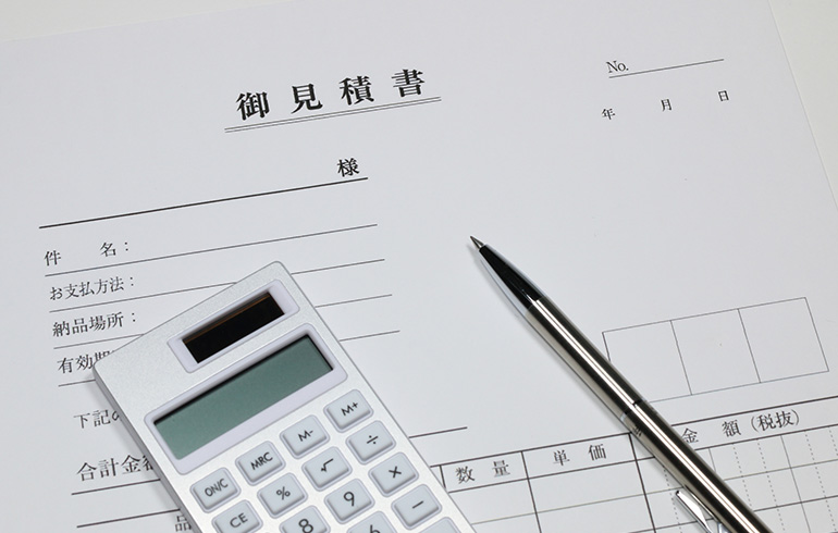 Japanese estimate form (御見積書) with a calculator and a pen on top, ready to fill out