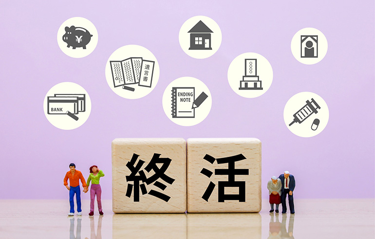 Two wooden blocks spell '終活' with small figures beside them; above, circular icons depict finances, banking, housing, legal documents, and healthcare symbols, illustrating end‑of‑life planning on a purple background.